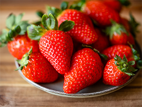 A bowl of fresh strawberries sitting on a counter.
